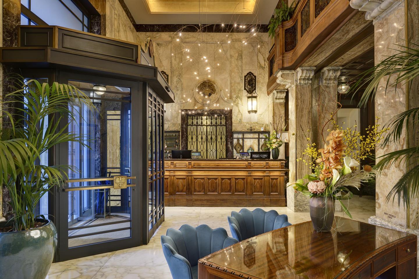 Elegant hotel lobby featuring a wooden reception desk, a revolving door entrance, and warm lighting
